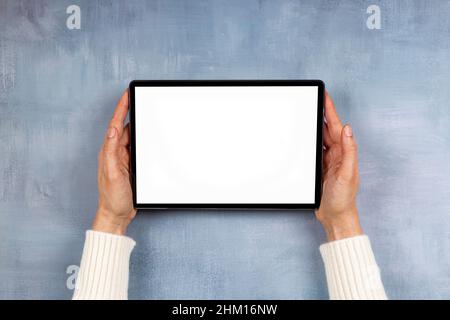 Frau Hand hält digitalen Tablet-Computer mit weißen Bildschirm Modell auf grauem Hintergrund. Draufsicht, Kopierbereich Stockfoto
