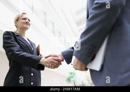 Geschäftsleute schütteln sich in der Lobby des Gebäudes die Hände Stockfoto