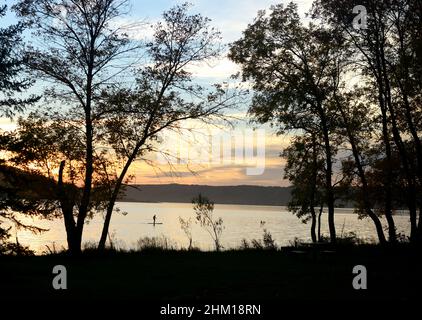 Paddle Boarder Silhouette gegen untergehende Sonne Stockfoto
