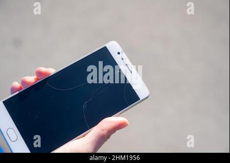 Frau hält Smartphone mit defekten Bildschirm im Freien. Stockfoto