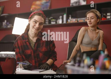 Attraktive Frau Tattoo Master Blick auf Kamera Stockfoto