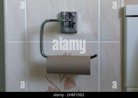 Leeres Toilettenpapierkartonrohr auf Metall-Toilettenpapierhalter. Stockfoto