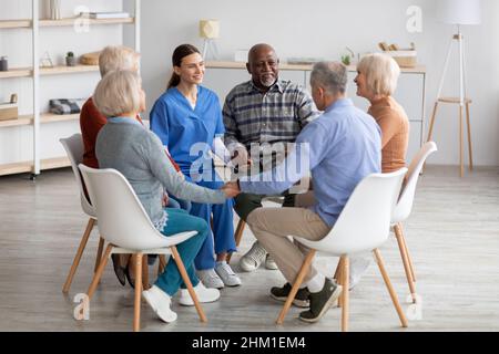 Positive junge Psychologin mit Gruppentherapie bei älteren Menschen Stockfoto