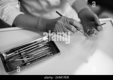 Hände weibliche Zahnärztin mit zahnmedizinischen Instrumenten Nahaufnahme. Schwarzweiß-Foto. Stockfoto