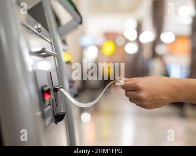 Eine Frau nimmt ein Zugticket von einem Selbstbedienungskartenschalter. Stockfoto