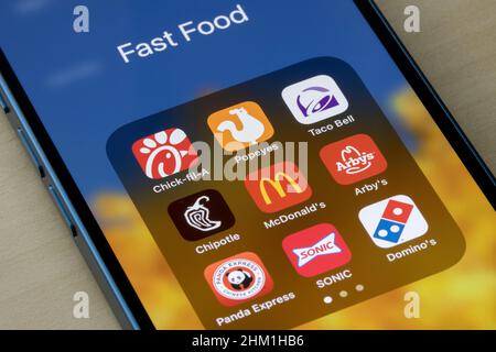 Auf einem iPhone sind verschiedene Fast-Food-Ketten-Apps zu sehen: Chick-Fil-A, Popeyes, Taco Bell, Chipotle, McDonald's, Arby's, Panda Express, SONIC und Domino's.. Stockfoto