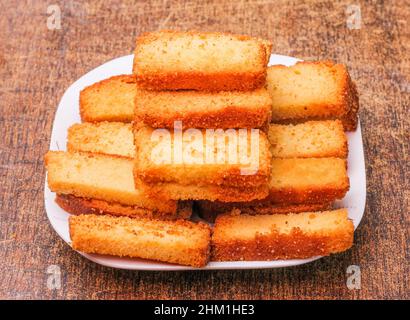 Knuspriger Kuchen Zwieback in einem Teller isoliert auf dunklem Holz Hintergrund Draufsicht Stockfoto