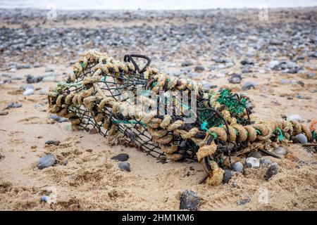 Cromer, Norfolk, Großbritannien – Februar 2022. Nahem und selektivem Fokus eines beschädigten Krabbenkännchen, Hummerkänfels oder einer Fischfalle, die am Strand von Cromer im Norden aufgegeben wurde Stockfoto