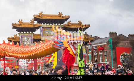 Der Dragon Dance geht im Februar 2022 während der Feierlichkeiten zum chinesischen Neujahr in Liverpools Chinatown durch den Paifang. Stockfoto