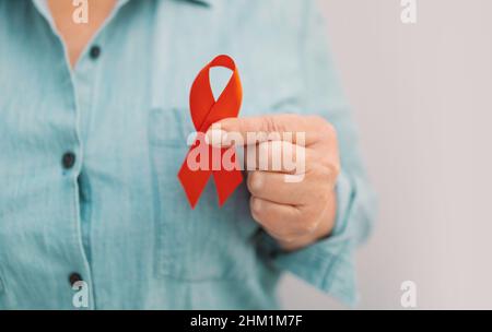 Frauenhänden mit rotem Band, HIV-Bewusstsein, Welt-AIDS-Tag, Welt-Krebs-Tag Stockfoto