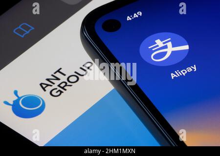 Das Alipay-App-Symbol wird auf einem Smartphone über einem iPad-Bildschirm angezeigt, auf dem die Homepage von Ant Group angezeigt wird. Stockfoto