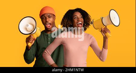Fröhlicher schwarzer Kerl und Dame mit Megaphonen, die Ankündigung machen Stockfoto