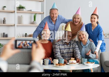 Positive Senioren und Krankenschwester feiern Geburtstag, fotografieren Stockfoto