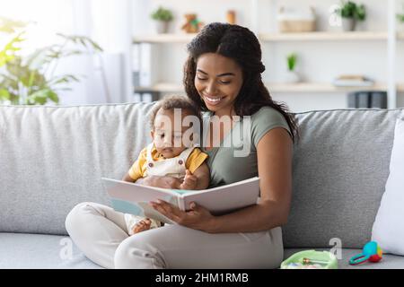 Porträt Von Caring Black Mom Lesebuch Zu Kleinen Baby Zu Hause Stockfoto