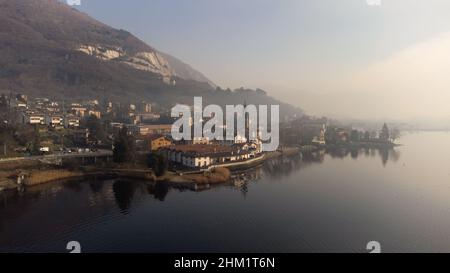 Morgennebel, der an einem kalten Wintertag über dem See schwebt. Reiseziel - Luftdrohnenansicht Comer See, Lombardei, Italien Stockfoto