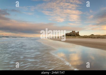 Sonnenuntergang bei Flut am Bamburgh Strand und Schloss an der Northumberland Küste, Nordostengland im Winter Stockfoto
