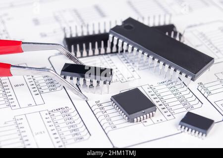 Elektronikkomponenten und Pinzetten auf dem Hintergrund des Schaltplans. Konzept für die Entwicklung und Konstruktion von elektronischen Geräten. Stockfoto