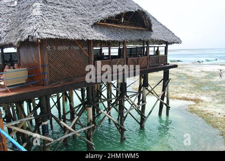 Hölzerner Pier und Strohdächer an einem tropischen Strand, Insel Sansibar. Stockfoto