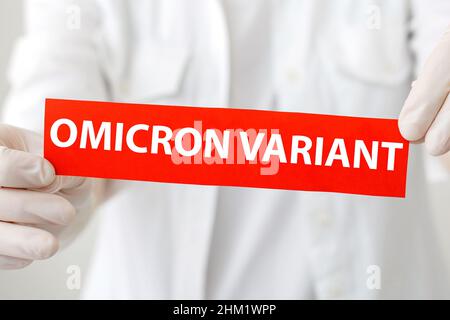 Omicron Variant Text Schriftzug rot Warnschild. Neue Omicron-Variante covid 19 in Arzthänden in weißem Fell und Handschuhen. Stockfoto