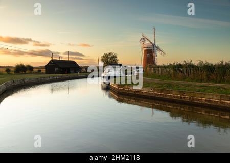 Boote, die bei Sonnenaufgang in der Nähe von Horsey Windpump im Broads National Park in Norfolk, Großbritannien, festgemacht haben Stockfoto