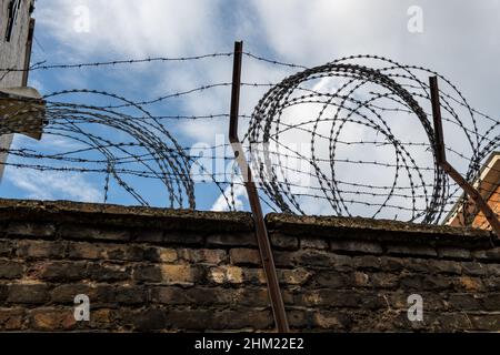 Ein Stacheldrahtzaun auf einer Ziegelwand. Stockfoto