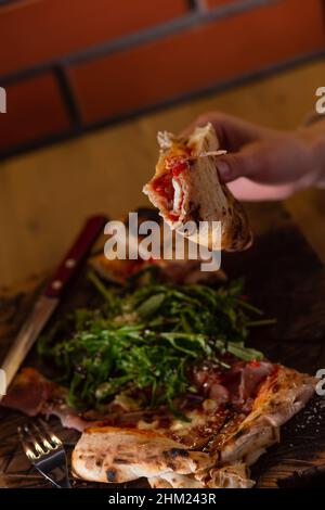 Nahaufnahme der Hände eines Mädchens, das in einem Café Bruschetta oder Pizza mit Kräutern und Sauce isst. Selektiver Fokus. Stockfoto