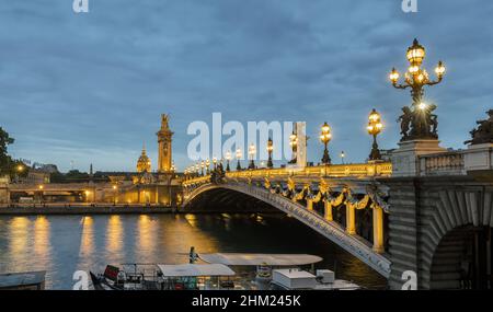 Brücke Pont Alexandre III über die seine und Hotel des Invalides bei Sonnenuntergang. Die Brücke ist mit kunstvollen Jugendstillampen und Skulpturen geschmückt. Paris, Fr. Stockfoto