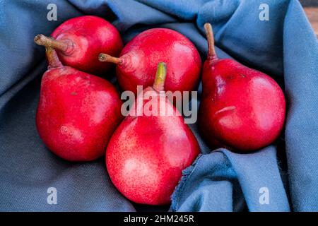 Eine rote Schlachterbirne oder rote Birnen auf einem blauen Tuch. Bio- und Naturprodukte. Gesunde Ernährung. Stockfoto