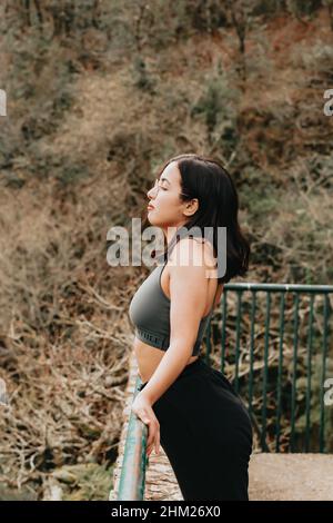 Junge arabische Frau auf Sportkleidung ruhen auf einem Bürgersteig, während der Blick auf den Horizont im Wald, während eines Herbsttages, Inspiration Bild mit Stockfoto