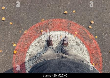 Der junge Mann steht im Herbst im Kreis auf den Straßen, persönlich pessive von oben. Stockfoto