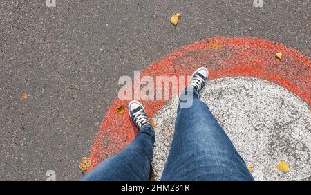 Junge Frau tritt aus einem Kreis auf die Straßen, persönliche Pespropective von oben. Stockfoto