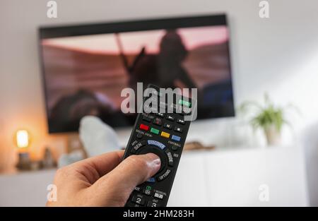 Fernbedienung und Fernsehen mit männlicher Hand Stockfoto