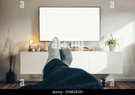 Mann, der in seinem Wohnzimmer Fernsehen schaut, aus der Perspektive. Stockfoto