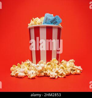 Aufnahme einer runden Popcornbox mit zwei blauen Tickets auf rotem Hintergrund. Ideal für Webseiten und Zeitschriften-Layouts Stockfoto