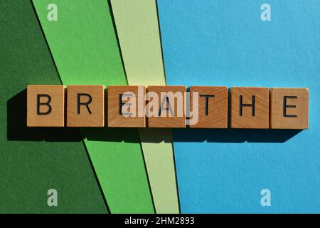 Atmen Sie, Wort in hölzernen Buchstaben auf grünem und blauem Hintergrund isoliert Stockfoto