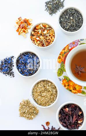Getrockneter Kräutertee. Auswahl an trockenem Tee in Utensilien, auf weißem Hintergrund Stockfoto