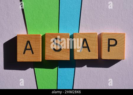 ASAP, Akronym für So bald wie möglich, in Holzbuchstaben, isoliert auf mehrfarbigem Hintergrund Stockfoto