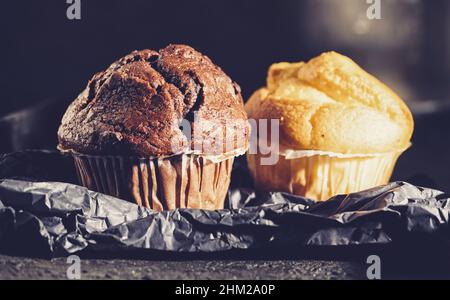 Schokoladenmuffin und Heidelbeer-Muffin, hausgemachte Bäckerei, auf dunklem Hintergrund Stockfoto