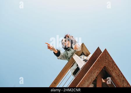 Auf dem Kopf stehende Aufnahme einer Frau, die überrascht auf etwas hinweist Stockfoto