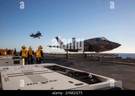 Matrosen der US-Marine mit der USS Makin Island beobachten, wie F-35B Lightning IIS, der Marine Fighter Attack Squadron (VMFA) 122 zugewiesen wurde, während Routinetrainings im Pazifischen Ozean an Bord von Makin Island landen. 2. Februar 2022. In Vorbereitung auf ihren bevorstehenden Einsatz mit der Marine Expeditionary Unit (MEU) von 13th und der Makin Island Amphibious Ready Group flog F-35Bs von VMFA-122 an Bord von Makin Island, während sie unterwegs waren, mit Elementen aus der MEU von 13th. (USA Marine Corps Foto von CPL. Quitte Bisard) Stockfoto