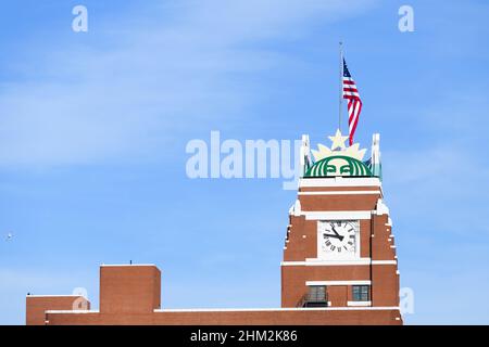 Seattle - 6. Februar 2022; Uhrenturm mit Logo am Starbucks Firmensitz in Seattle vor blauem Himmel mit US-Flagge Stockfoto