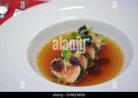 Nori wickelte Lachsrolle mit geschnittenen schwarzen Trüffeln und Sprossen in Suppenschüssel Stockfoto