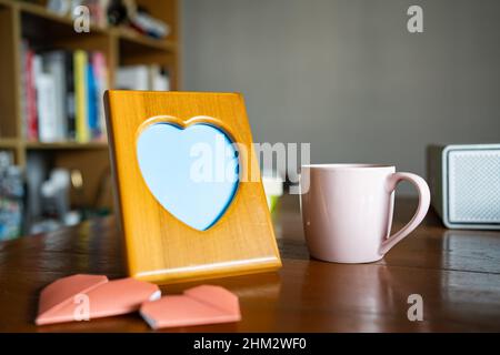 Herzförmiger Bilderrahmen aus Holz auf einem Arbeitstisch Stockfoto