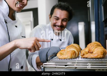 Junger lateinischer Bäcker und Backen von Croissant und Brot im Ofen in der Küche in Mexiko Lateinamerika Stockfoto