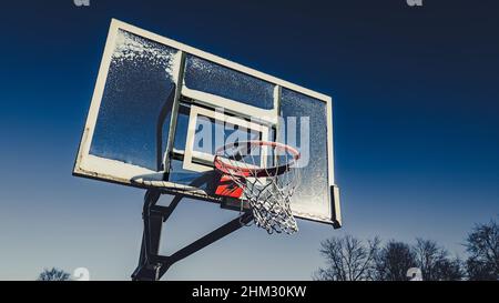 Eine gefrorene Szene mit einem Basketballkorb, der mit Schnee bespritzt ist. Stockfoto