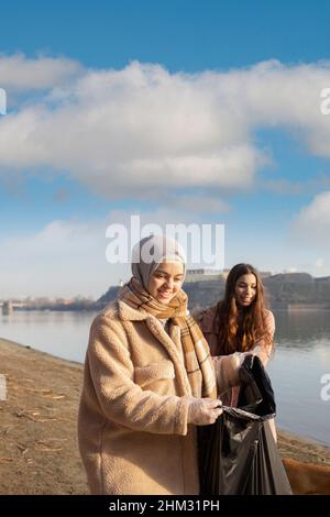 Junge Frau, die den Müll von einem Strand abholt Stockfoto