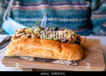 Butterbrioche mit Schweinebrippen. Köstliche Mahlzeit der spanischen Fusion-Küche, wunderschön dekoriertes Gericht auf einem Teller, der von einem spanischen preisgekrönten Beruf zubereitet wird Stockfoto