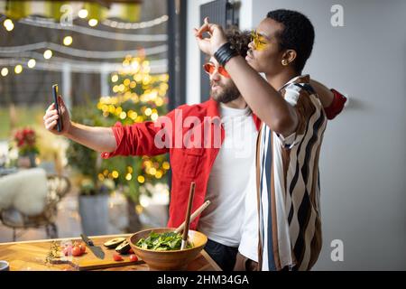 Zwei bunt gekleidete, stylische Jungs, die in Innenräumen Selfie am Telefon machen Stockfoto