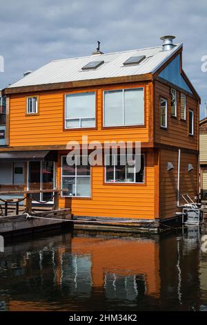 Oranges hölzernes Bootshaus am Wasser mit Spiegelung. Straßenansicht, Reisefoto, niemand, selektiver Fokus Stockfoto