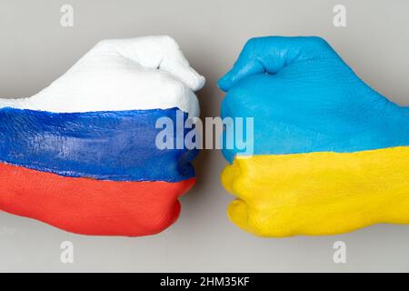 Flaggen der Ukraine und Russlands Flagge auf Händen schlagen sich gegenseitig auf hellgrauem Hintergrund der Weltkarte, Ukraine vs. Russland im Krisenkonzept des Weltkriegs Stockfoto